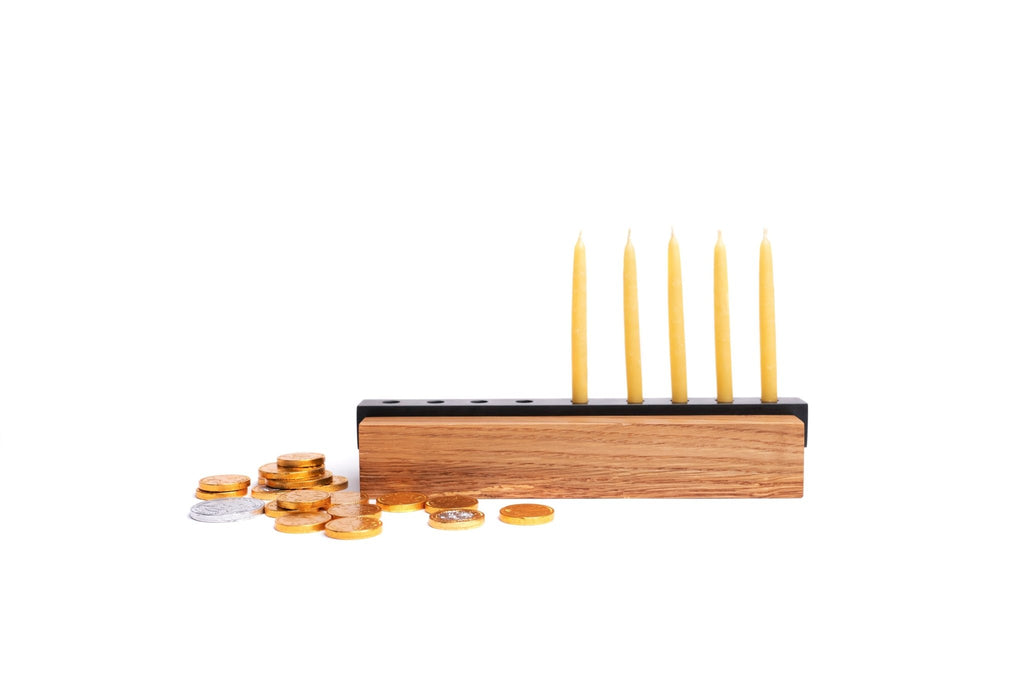 Wood and Steel Menorah viewed from the side with yellow candles and gold coins