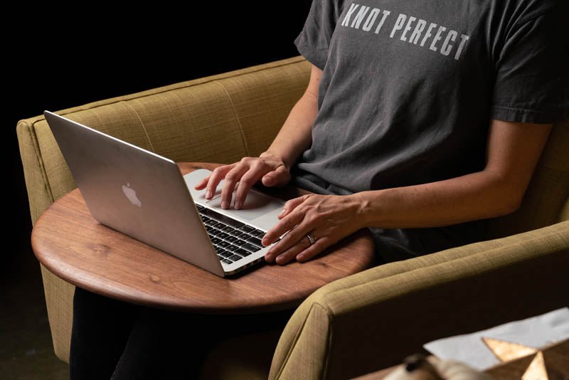 a person sitting in a chair using the wooden Lap Desk to work on their laptop