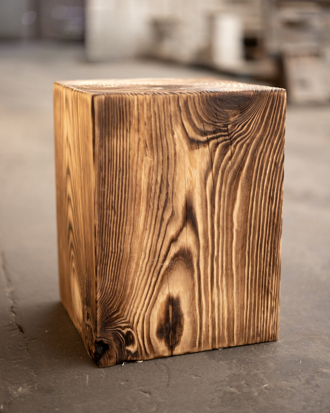 Wooden cube on a concrete floor with a blurred background