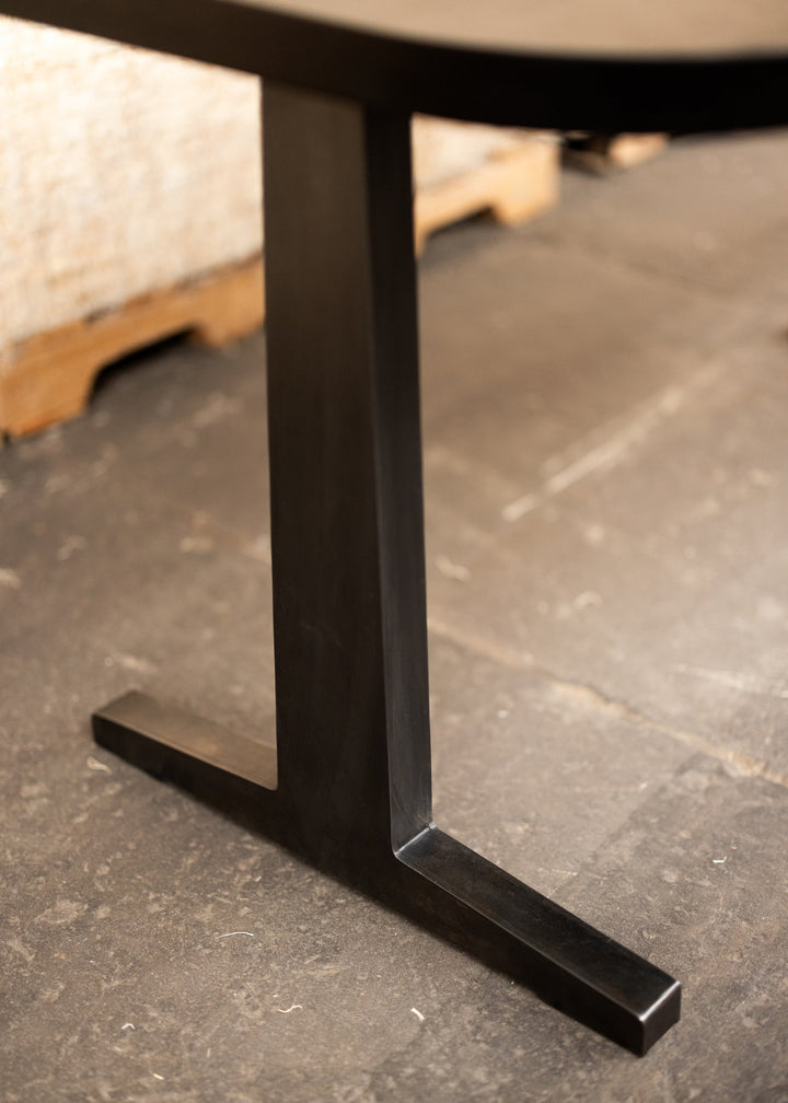 Close-up of a black metal table leg on a gray concrete floor.