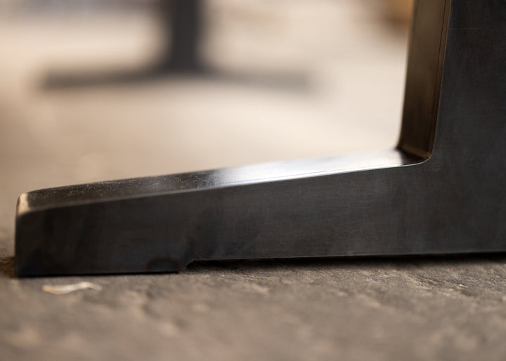 Close-up of a black metal table oedestal foot edge on a blurred background