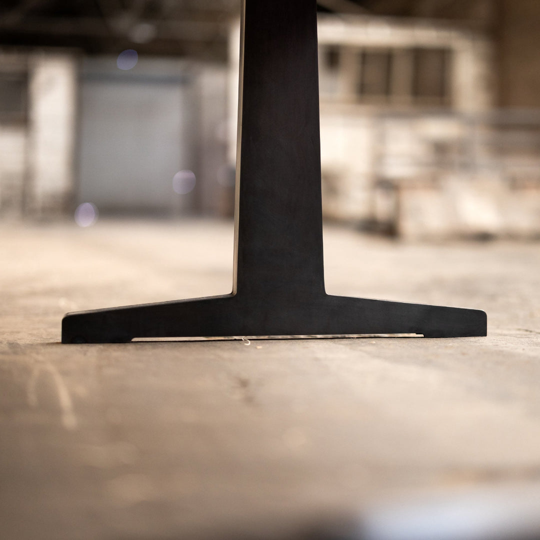 Close-up of a black metal pedestal table base on a blurred background