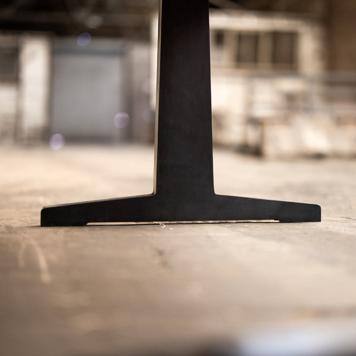 Close-up of a black metal pedestal table base on a blurred background