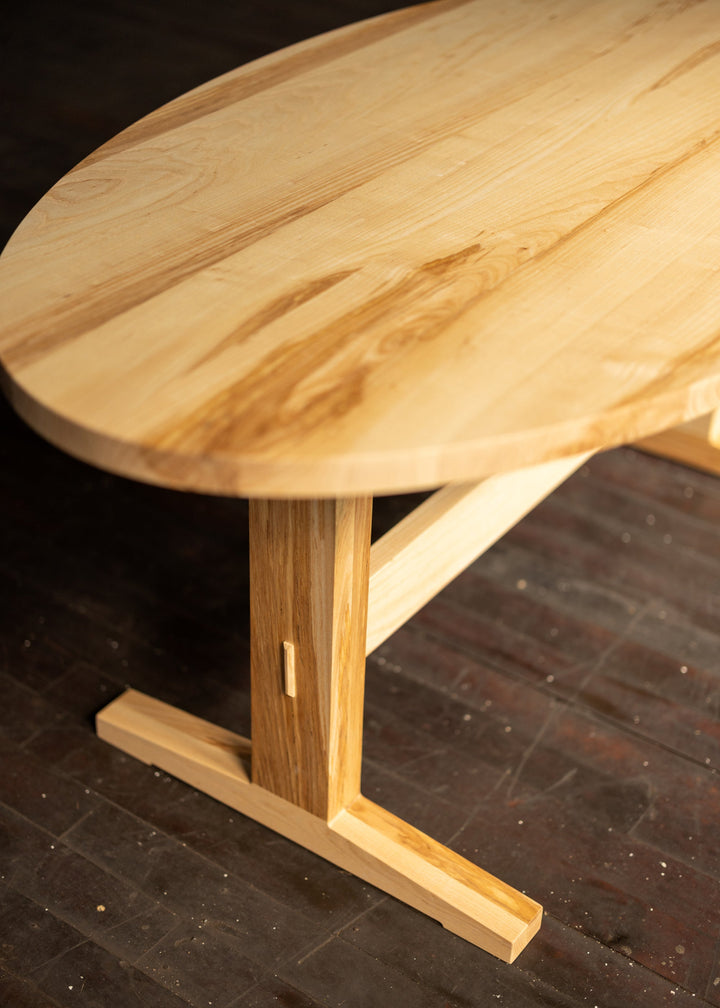 Wooden oval dining table with a dark floor background