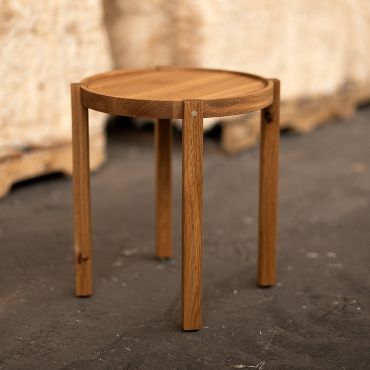 Wooden side table on a dark floor with a blurred background