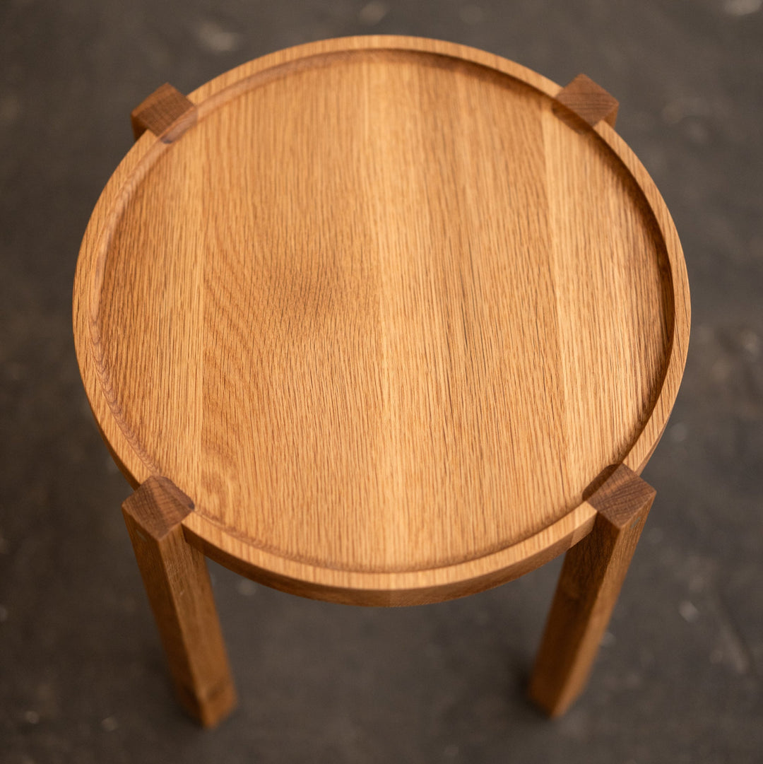 Wooden side table with a round top on a dark textured background