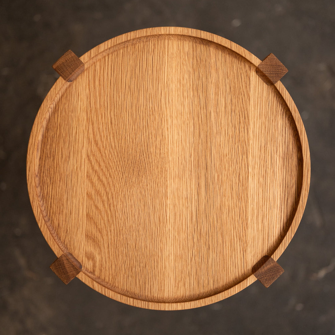 Wooden round occasional table with four legs on a dark textured background