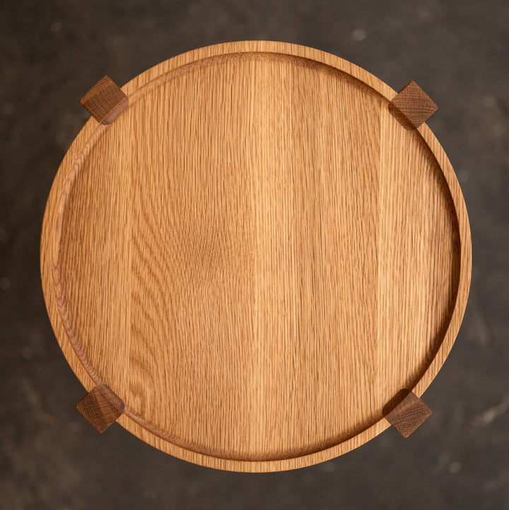 Wooden round occasional table with four legs on a dark textured background