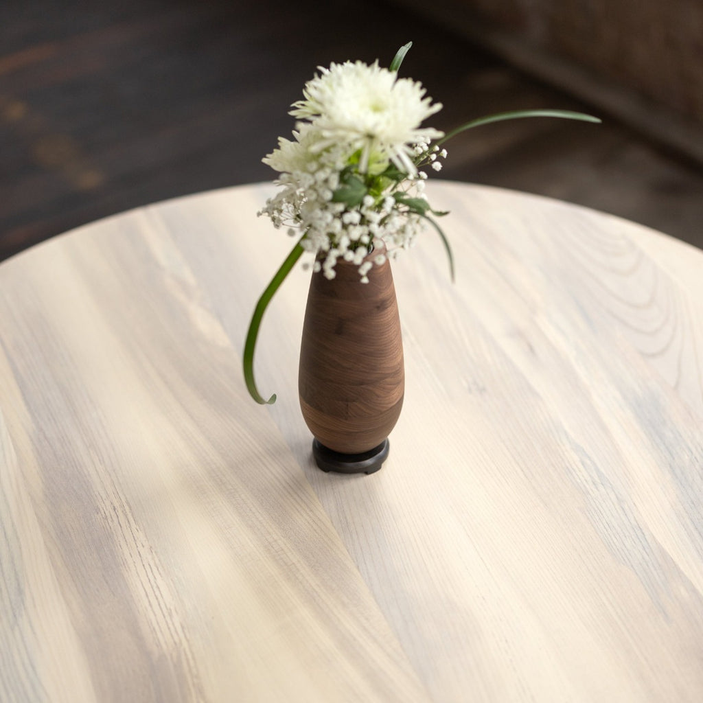 Round Wood and Bronze Pedestal Base Dining Table top with vase
