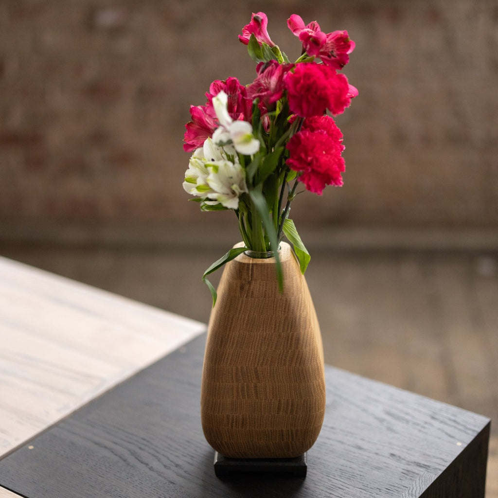 Wooden vase with flowers pictured on a wood cube